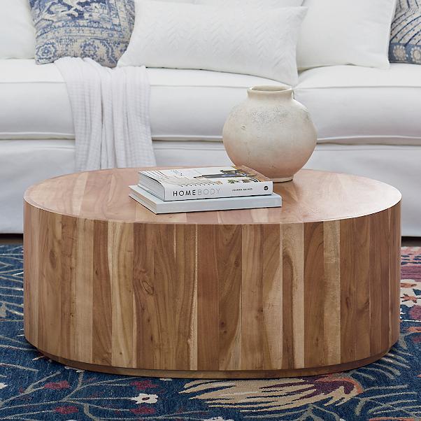 drum wooden coffee table with coffee table books and vase on top. 