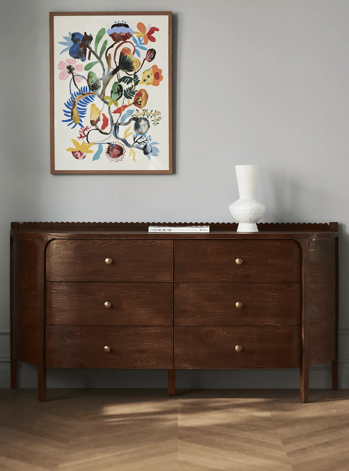 Brown traditional dresser with scalloped detail and decorative objects. 