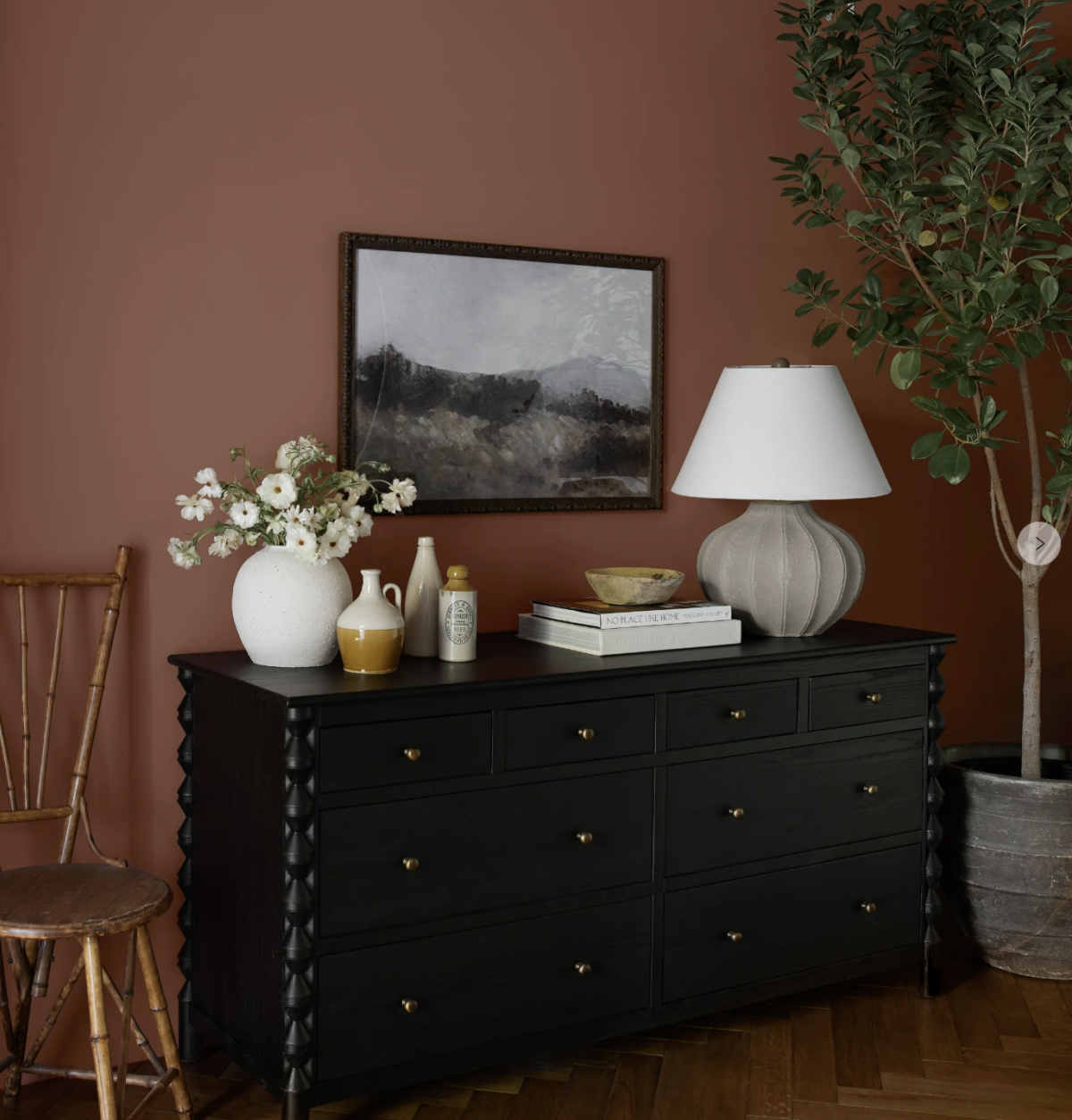 wide scalloped black dresser with a lamp and decorative pieces on top. 