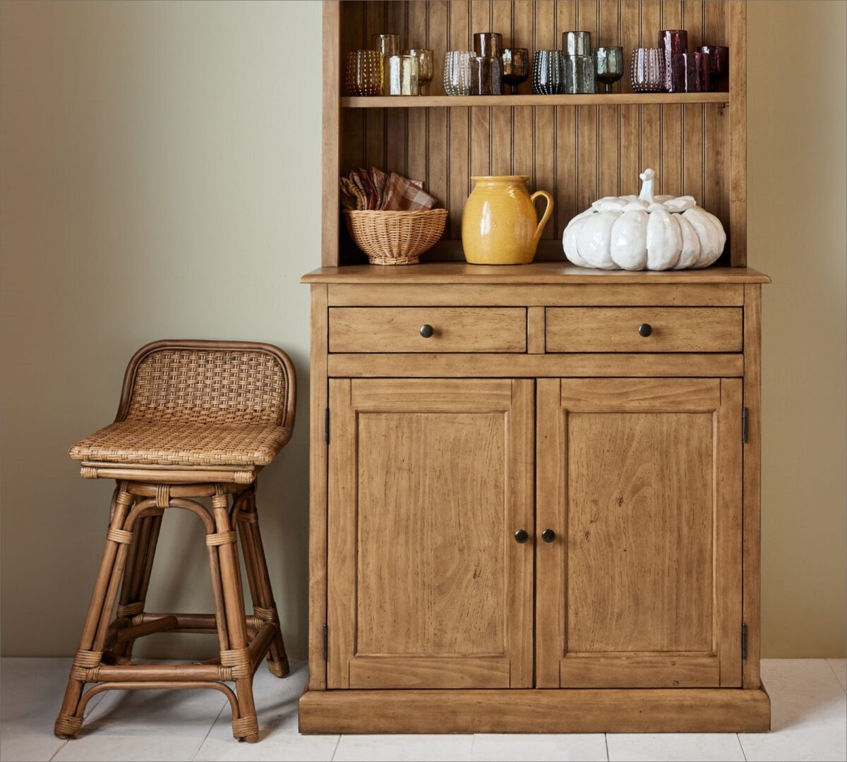 rattan swivel counter stool next to a wooden shelf with home decor items. 