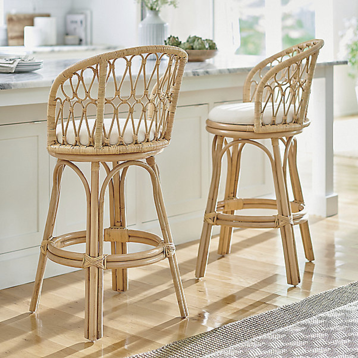 2 swivel bar and counter stools with white cushions at a kitchen island. 