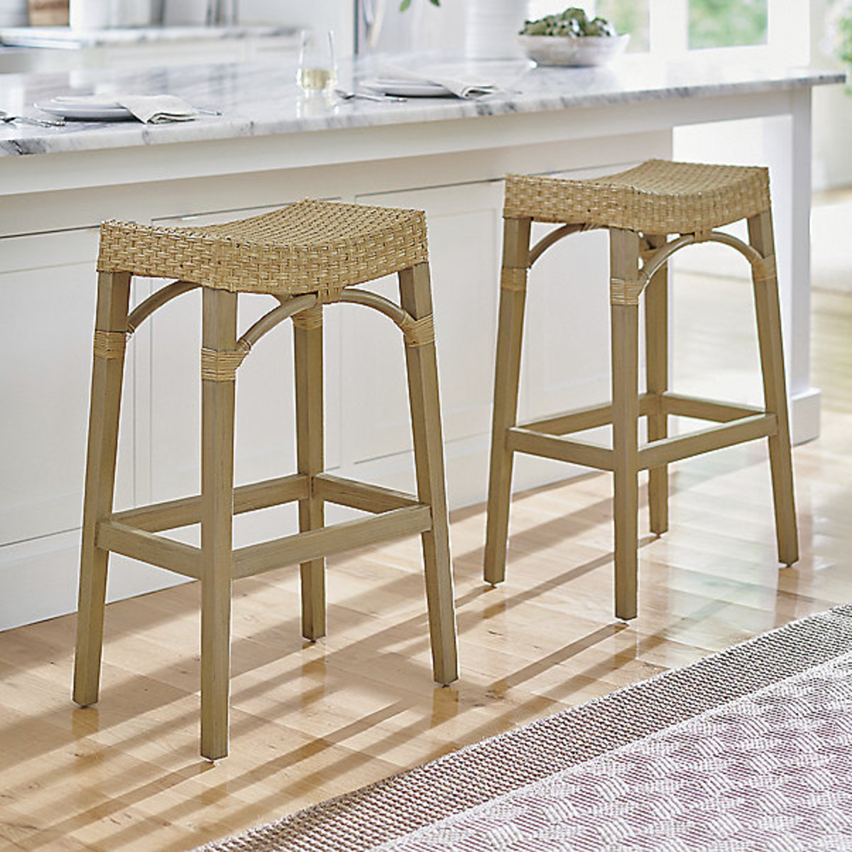 2 rattan wicker and mahogany wood counter stools at a kitchen island. 